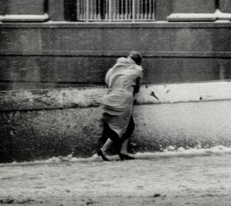 A pedestrian battles gusting winds at Bay and Front Sts