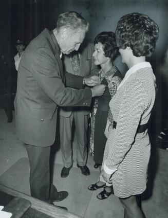 Widows of slain policemen accept medals for husbands, Chief Adamson pins decoration on Eileen Sinclair, Barbara Irwin looks on