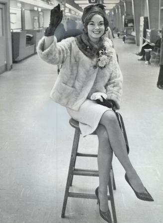 Prettily perched, Marlene Leeson of Huntsville, Miss Dominion of Canada, waits at Malton for plane which took her to London yesterday for Miss World Contest