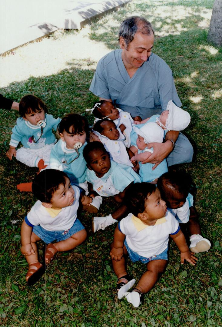 Pediatrician Jack Newman enjoys a true twinning experience yesterday during a reunion of mothers and twins born last year at Doctors Hospital. The number of twin births doubled in 1992. Story/A4