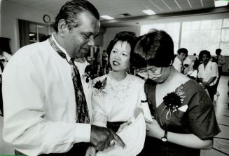 Helping hand: English-as-a-second-language teacher Erminia Ko, centre, gives graduation certificates to students Klet Lan Chau, right, and Deonaraine Deonaraine