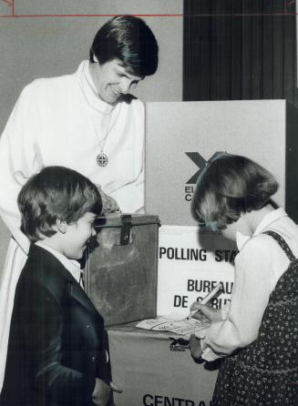 Rev. Philip Johnson watches Laurie Christensen, mark mock ballot. Darryl Jameson, looks on