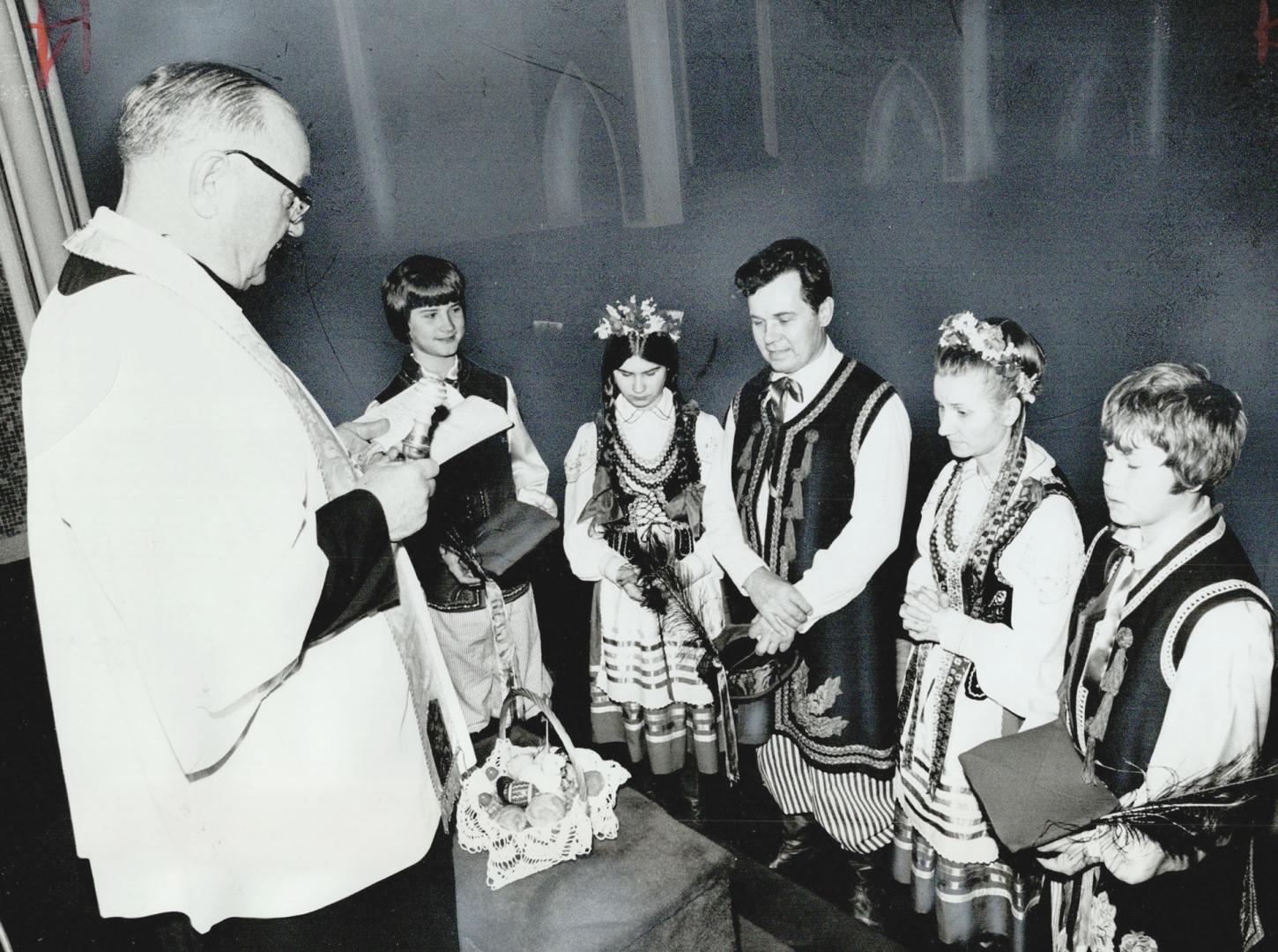 Father Felix Kwiatowski blesses the Dubickis basket of Easter food at St