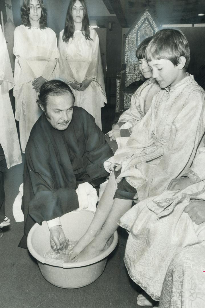 Re-enacting the last supper. Rev. Vasilios Roumanas of St. Demetrious Greek Orthodox Church washes the feet of Meni Tzanis, 9, while Chris Boozalas, 1(...)