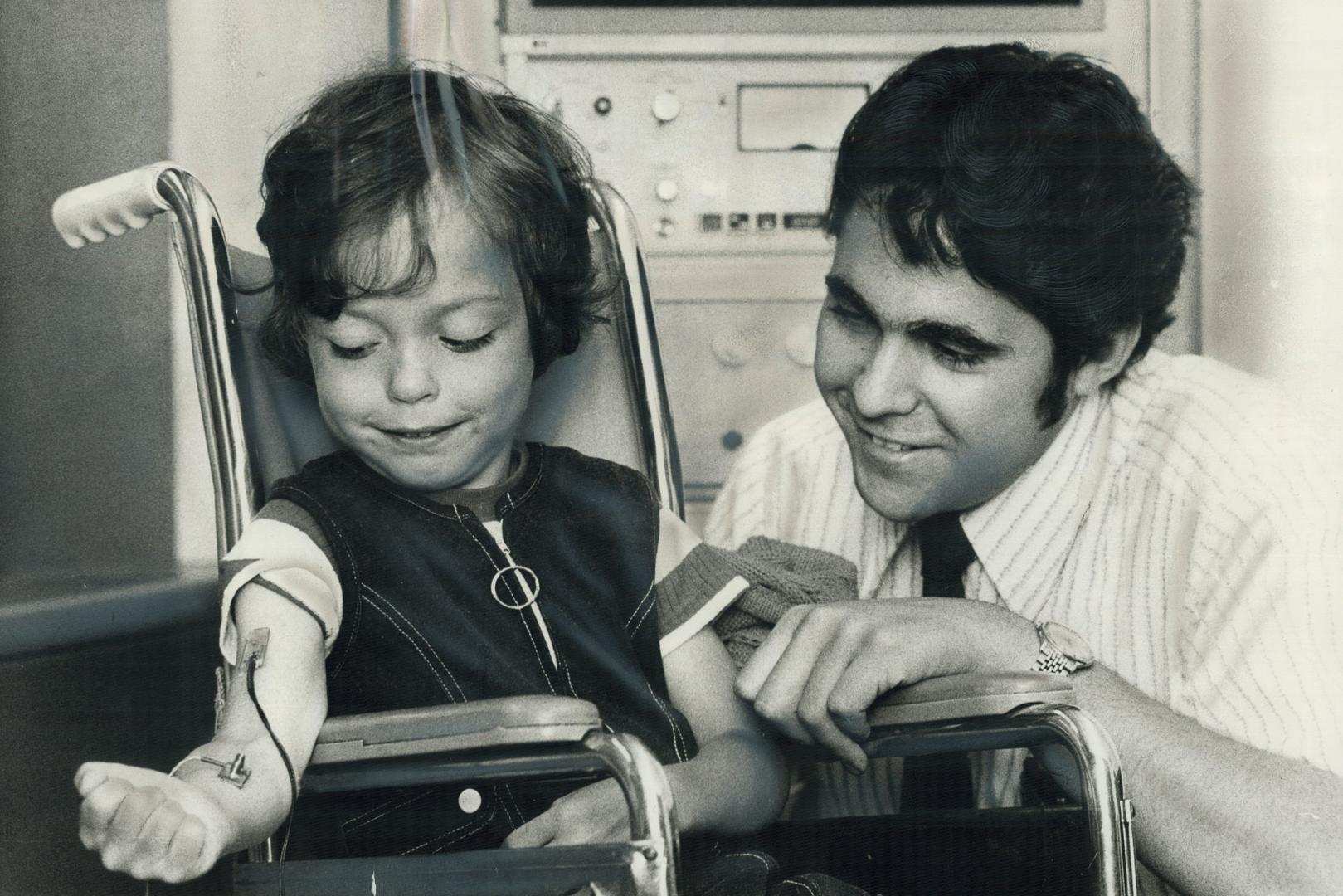 Electronic machine attached by wires to Christopher Malone's arm is helping him learn to control his limbs