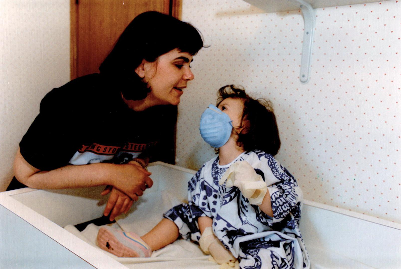 Role Reversal: Talla D'Aversa, 2, tries on the mask and gloves her mother Mary must use to clean and maintain the tube that connects the little girl to an intravenous feeder