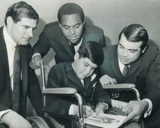 Guest of honor 'Timmy', who is 11-year-old Ian Walmsley of Oshawa, autographs menu of Kapp (right), quarterback of Minnesota Vikings of National Footb(...)