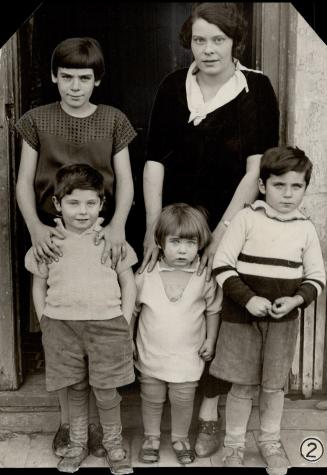 shows Mrs. Peter Romas of Brock Ave. with four of her children. Mrs. Romas claims to have seven eligible children and expects another any time now, wi(...)