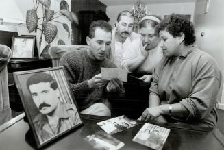 Anxious family, Shumal Orahan, left, Daniel Orahan, Nina Yonan and Jiindnia Tarrou study photographs as they wait for Khawa Koshaba and Yousif Orahan (in framed photo at front) to get visas