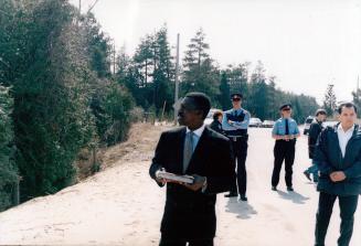 Judge Hugh Fraser, black, in suit, at Ipperwash shooting site