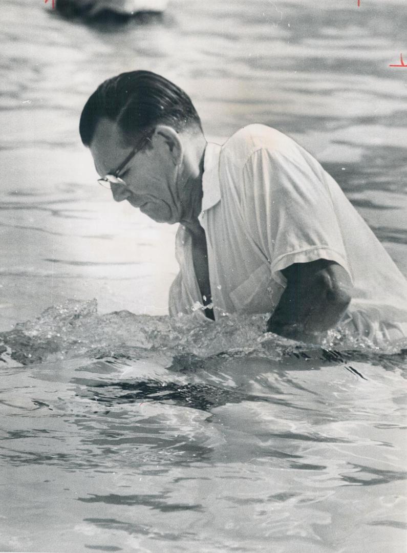 Down she goes . . . , Baptizer Jack Lynn of California ducks one of the 483 Jehovah's Witnesses taking part in a combination baptismal and ordination (...)