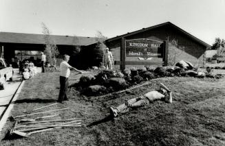 One workman takes a breather while his associates put some finishing touches on the site of the new hall