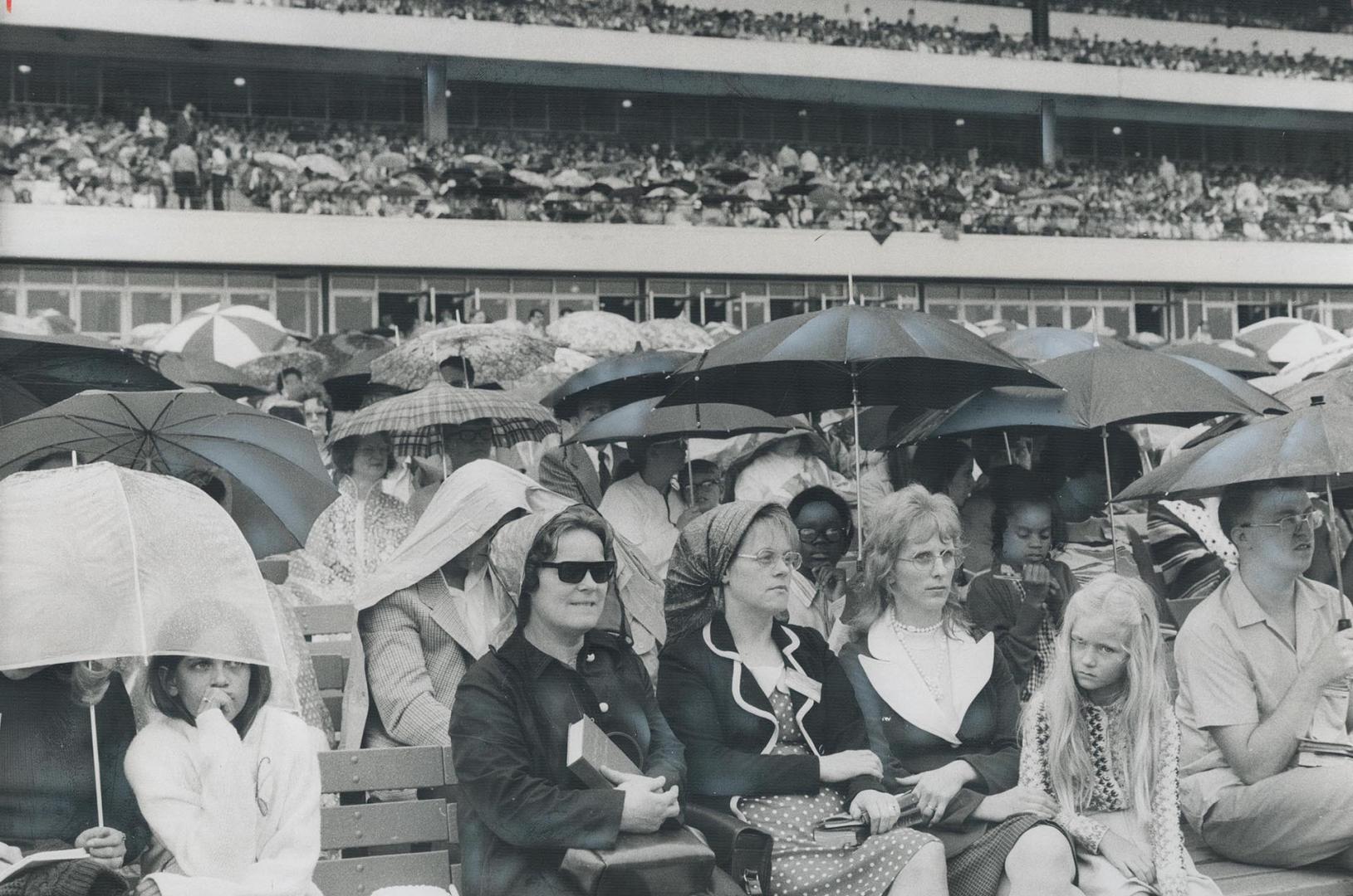 Umbrellas blossom in the stands at Woodbine racetrack yesterday as rain pours down on the Divine Assembly of Jehovah's Witnesses, some of whom came fr(...)