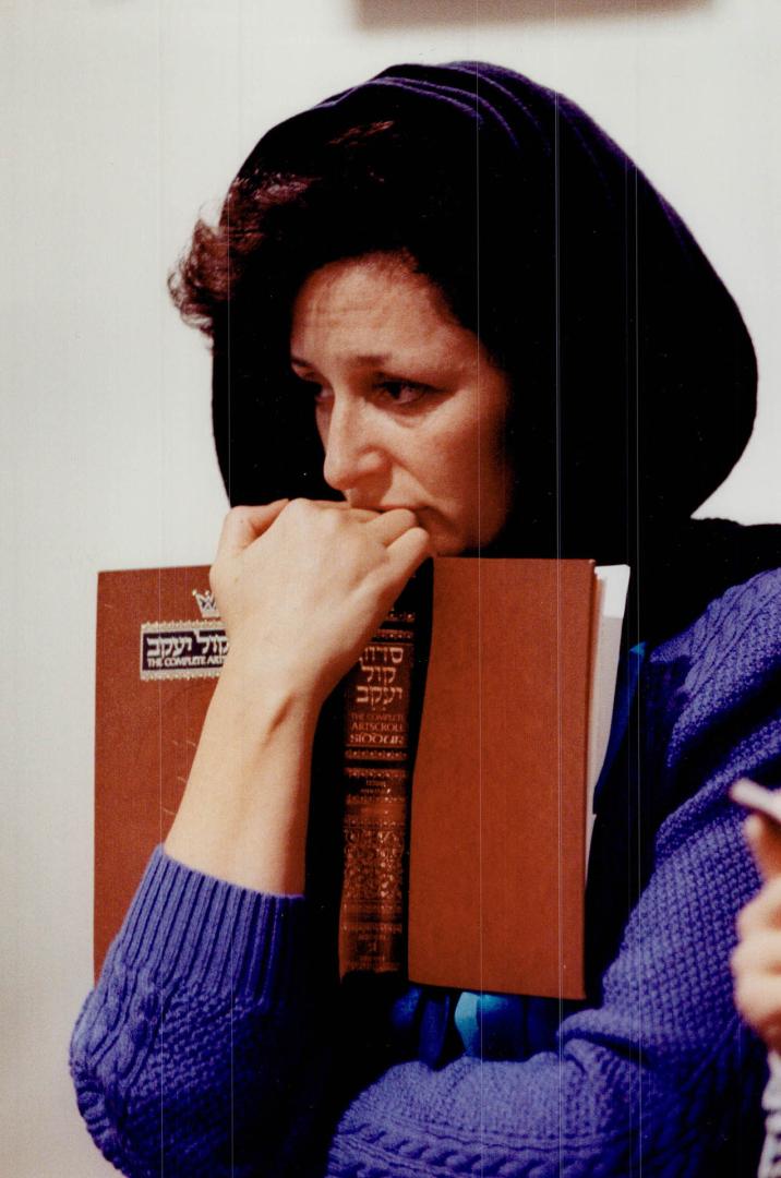 Sad vigil: A woman clutches her prayer book in Beth Avraham Yosef synagogue in Thornhill as Jews held prayer services last night after the Iraqi missile attack on Israel