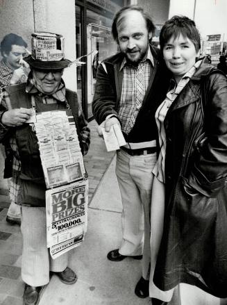 Twice lucky? Daniel Skellett of London and his wife, Bonnie, have picked up ther $100,000 Wintario cheque but they aren't stopping there. Skellett more tickets from vendor Clem Ferreira. [Incomplete]