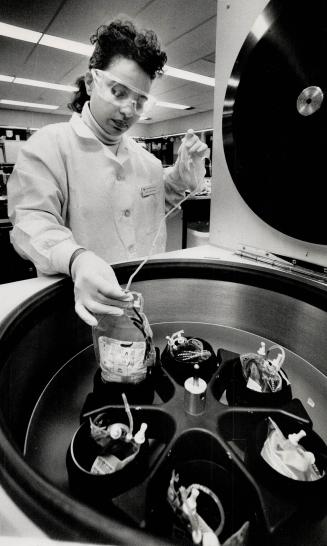 Lab technician Zaid Tesfagiorgis removes bags from a centrifuge used to separate plasma from red blood cells