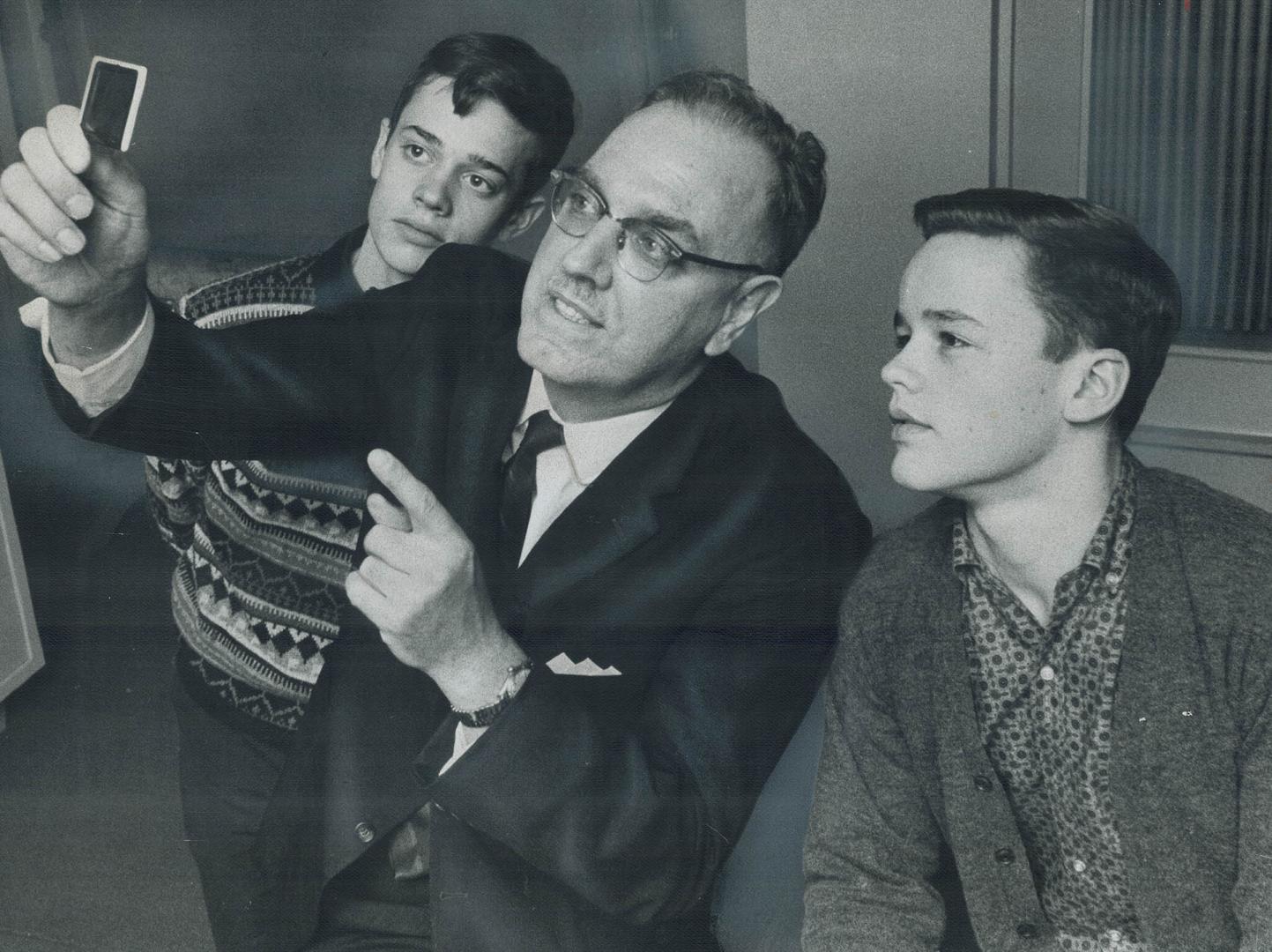 Colored slide of lung cancer is held up for examination, From left are John Millington, Dr. Norman Delarue and Douglas Millington