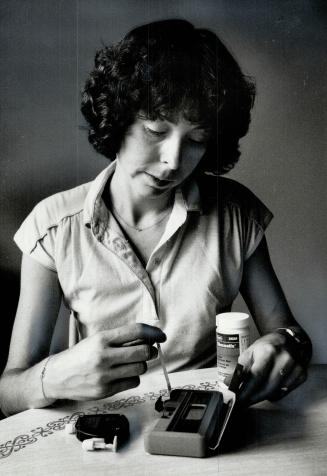 Testing blood: Diabetic Marilyn Carden of Bramalea puts a drop of blood on a test strip and inserts the strip into a blood glucose monitoring machine as part of experimental routine