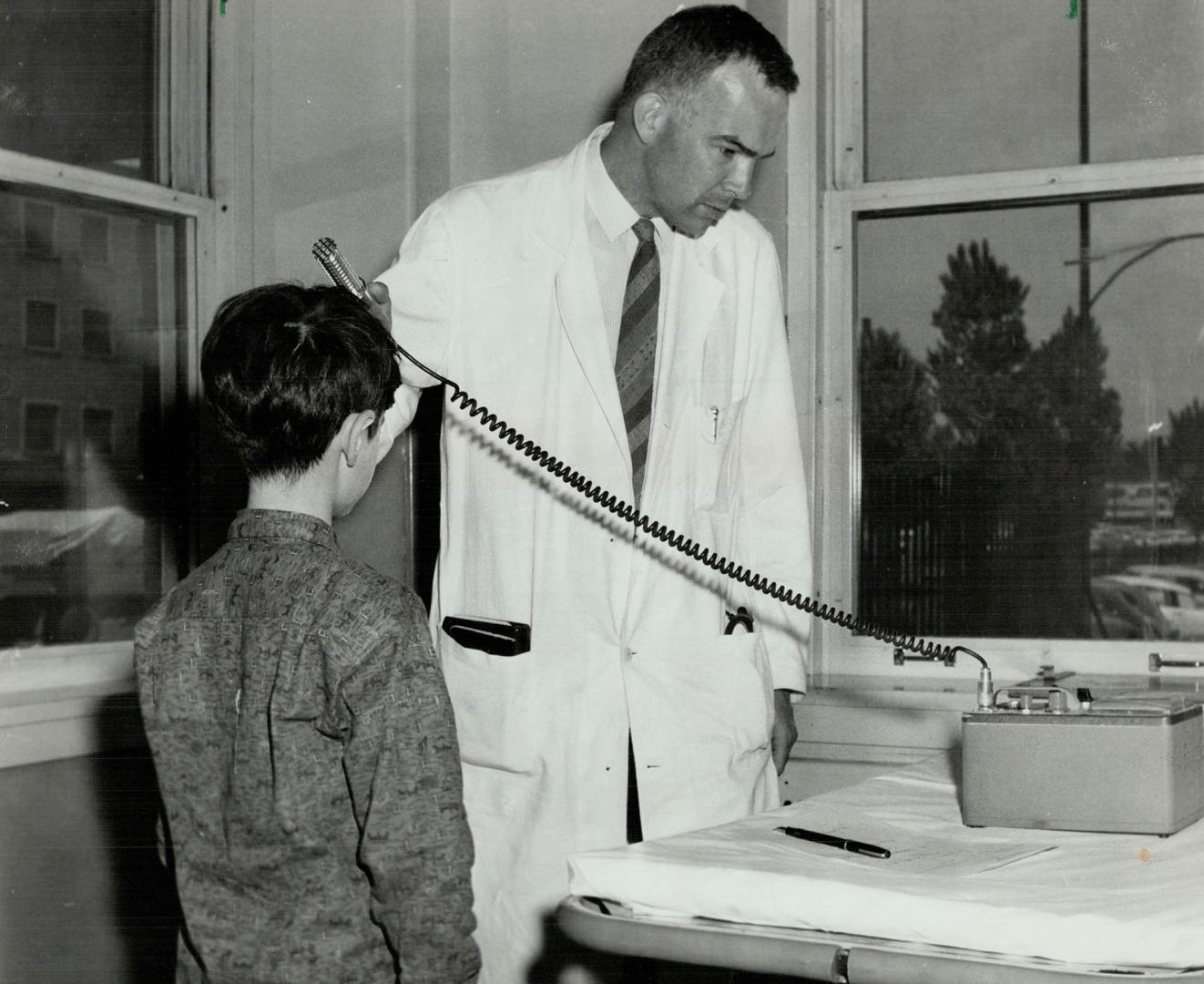 Brian Lachapelle is given geiger counter test by Dr. R. J. Slater