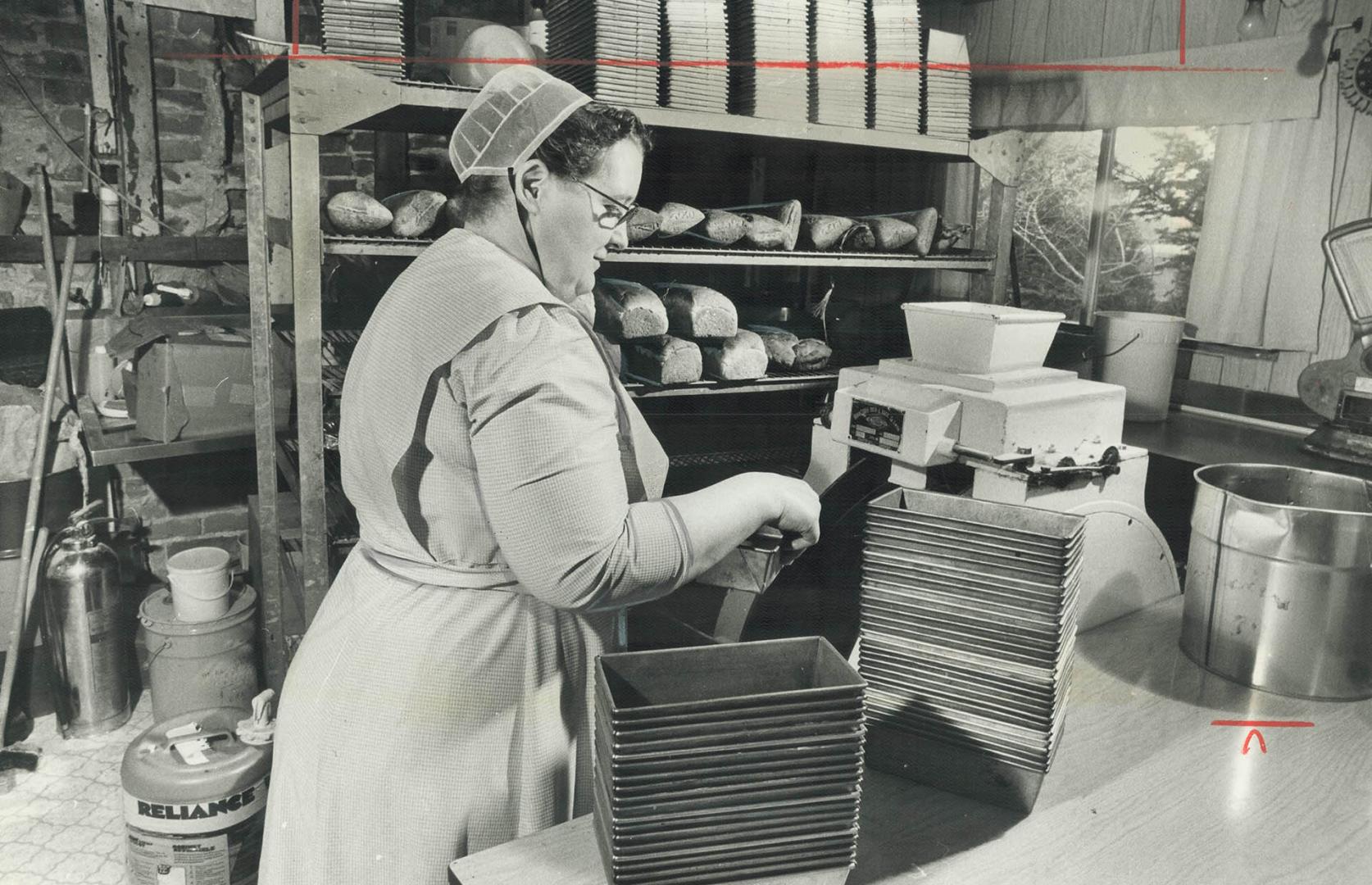 Rita Brubacher works at a dough-mixing machine in her home bakery, preparing a fresh batch of bread for the oven