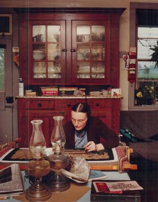 Her head bent low over a rough wooden frame, Elvina Martin works on a hooked rug like the ones that will be sold this Saturday in aid of the world's needy