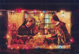 Felician Sisters Kim Maria, left, and Camillia carefully place the infant Jesus in the hay-filled Nativity scene assembled at the Roman Catholic order's mother house in Mississauga