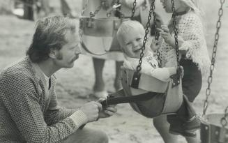 The littlest swinger, Tiny Sam McNair, 9 months, is strapped into a High Park playground swing by his dad Bob, so he'll be safe while dad watches over(...)