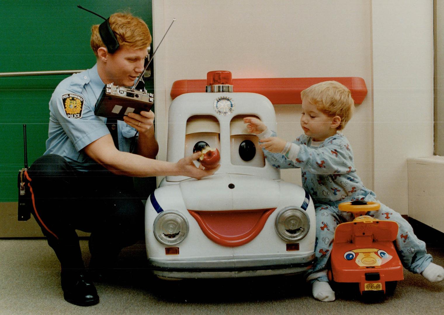 Nicholas MacPherson, 2, a patient at Credit Valley Hospital in Mississauga, is paid a friendly visit by Constable Jim Currie of Peel Regional Police ((...)