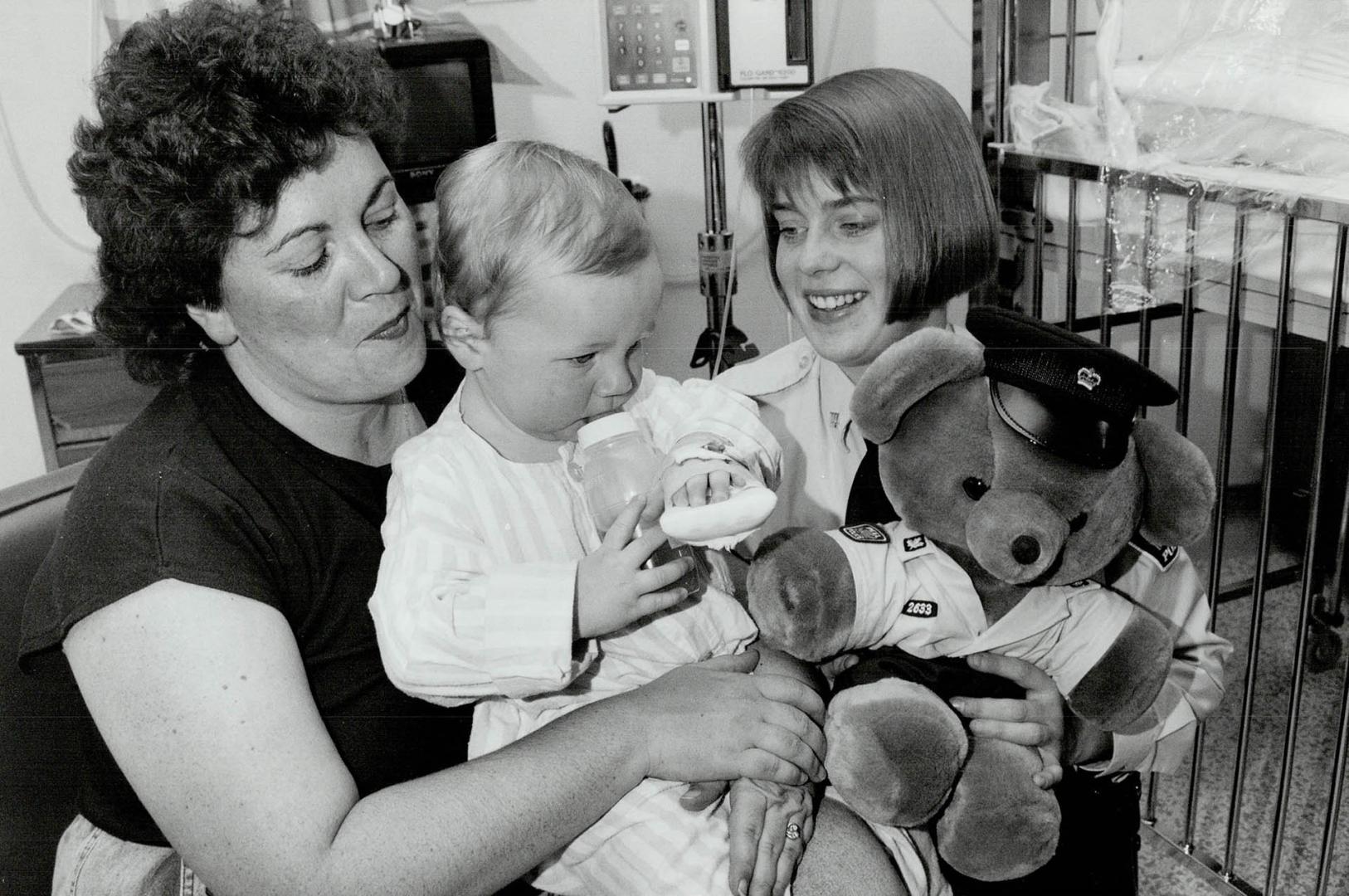 Peel Region Constable Lora Iusi presents Mitchell Jacobs, held by mom Kelly, with a teddy bear at Peel Memorial Hospital yesterday. Iusi saved 18-mont(...)