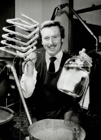 Why is this man smiling? You might be smiling, too, if you were RCMP Constable Carl Broughton and holding a gallon of moonshine, part of 35 gallons of(...)