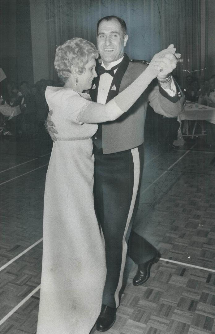 Assistant Commissioner E. R. Lysyk of the Royal Canadian Mounted Police and his wife open the RCMP centennial ball last night at force headquarters