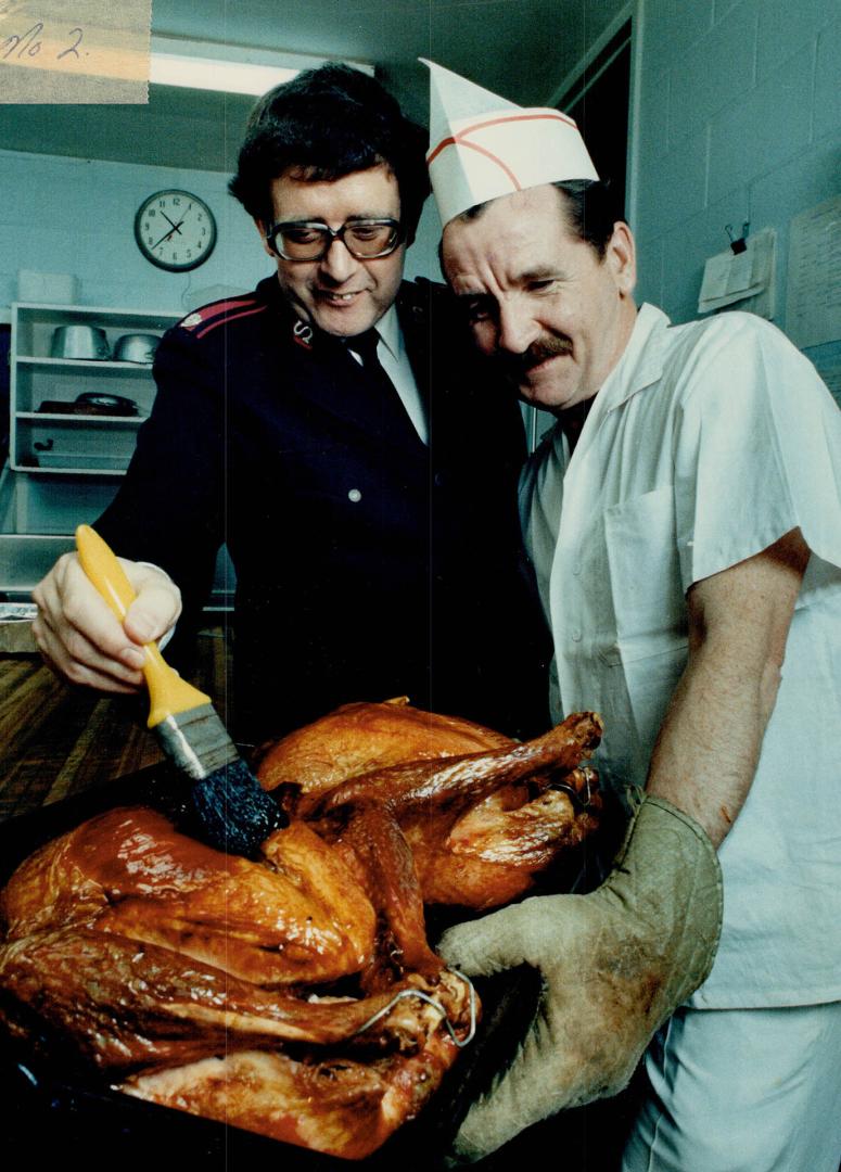 Christmas cheer: Salvation Army's Major Reg Newbury helps chef Des Banks baste one of the many turkeys for Christmas dinner for the city's disadvantaged