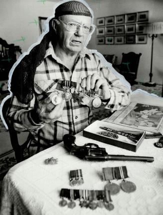 Spoils of war: Martin wearing camouflage net (far left), displays medals and pistol he used in battle, and with captured Nazi flag