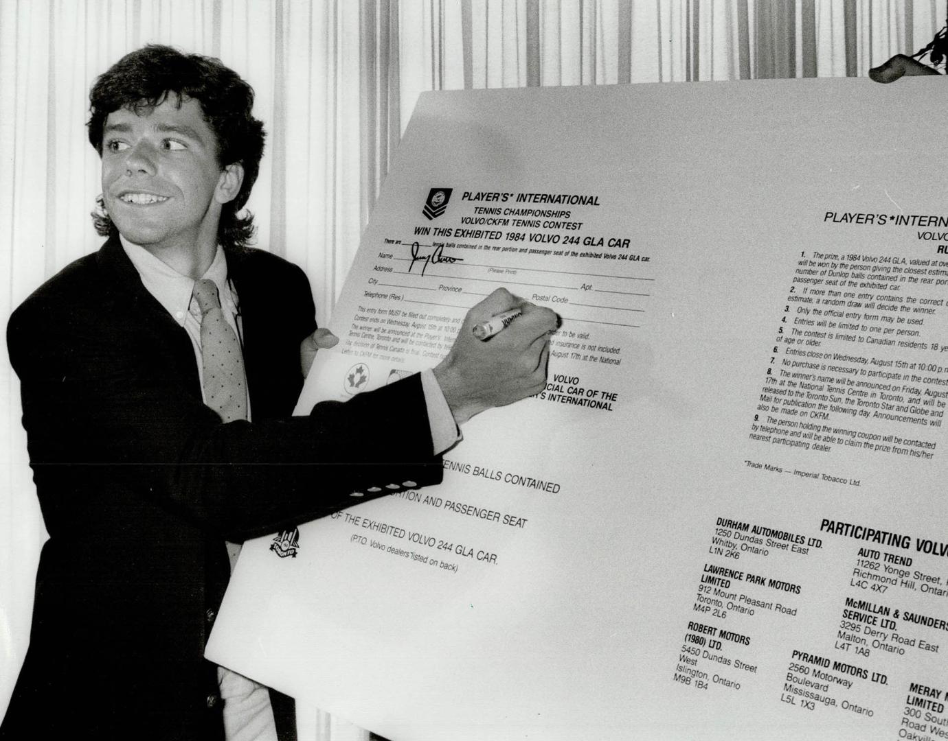 Signing up: Jimmy Arias signs a giant-sized copy of the contest form for next month's Players International tennis tournament at press conference yesterday in the Westin Hotel