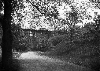 Image shows a road view with a bridge over it.