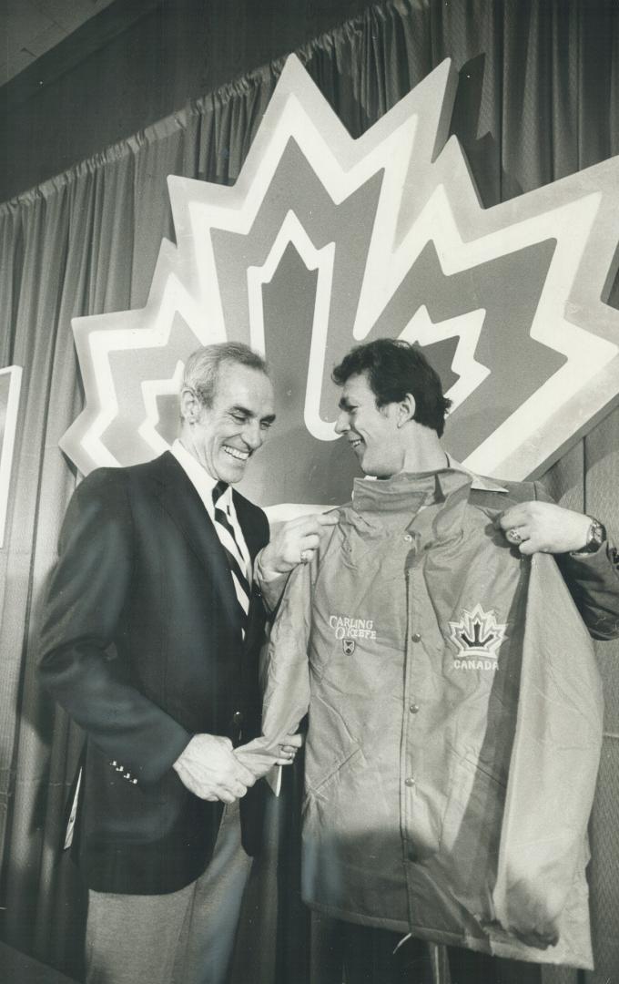 Team Canada coach Harry Howell, left and Penguins' Jean Pronovost examine team jacket at press conference called to announce squad that will represent(...)