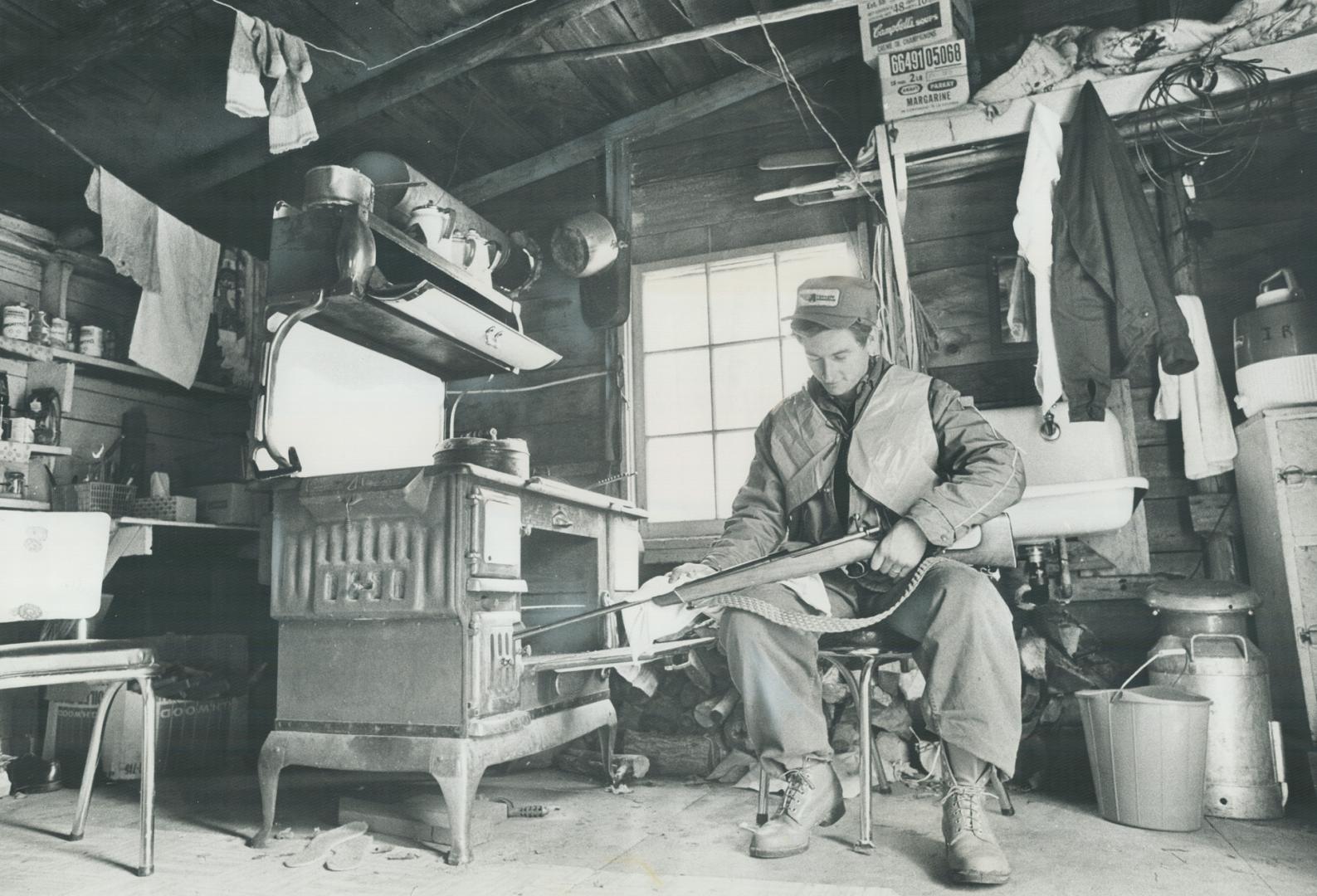 Hunter Murray Williamson cleans his rifle in camp