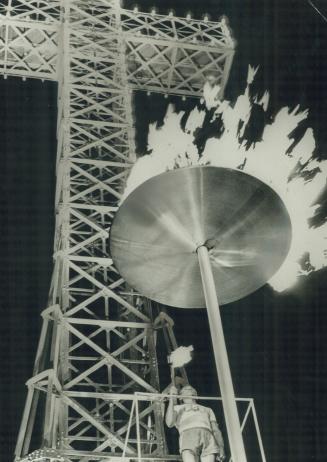 Olympic Urn atop Mount Royal is lit last night by Gerard Cote, 63, a marathon runner who is legendary in Quebec province. Flame lights up giant cross (...)