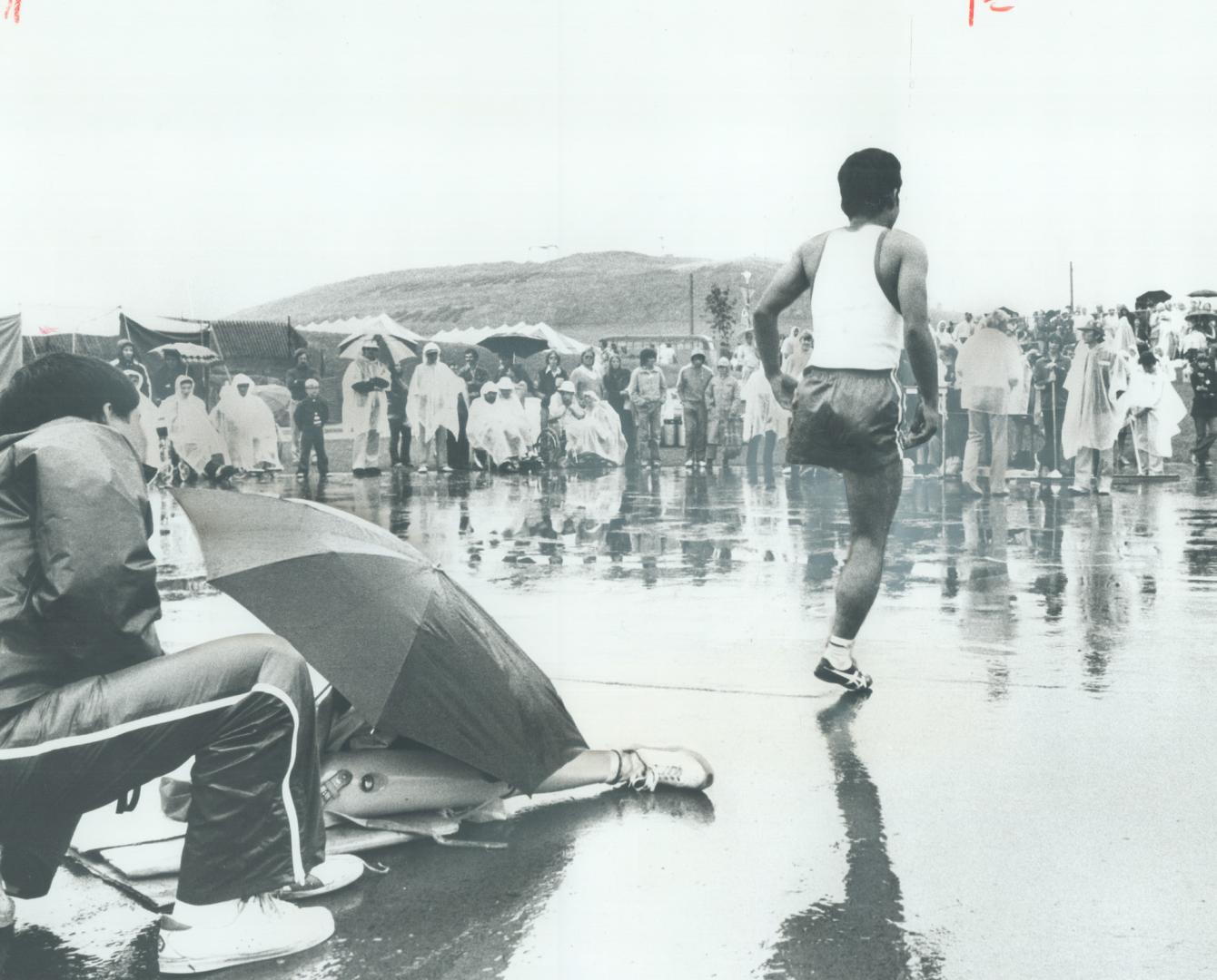 Here's a new way to warm up, This unidentified competitor at the Olympiad for the Physically Disabled moved out from under his umbrella to warm up for(...)