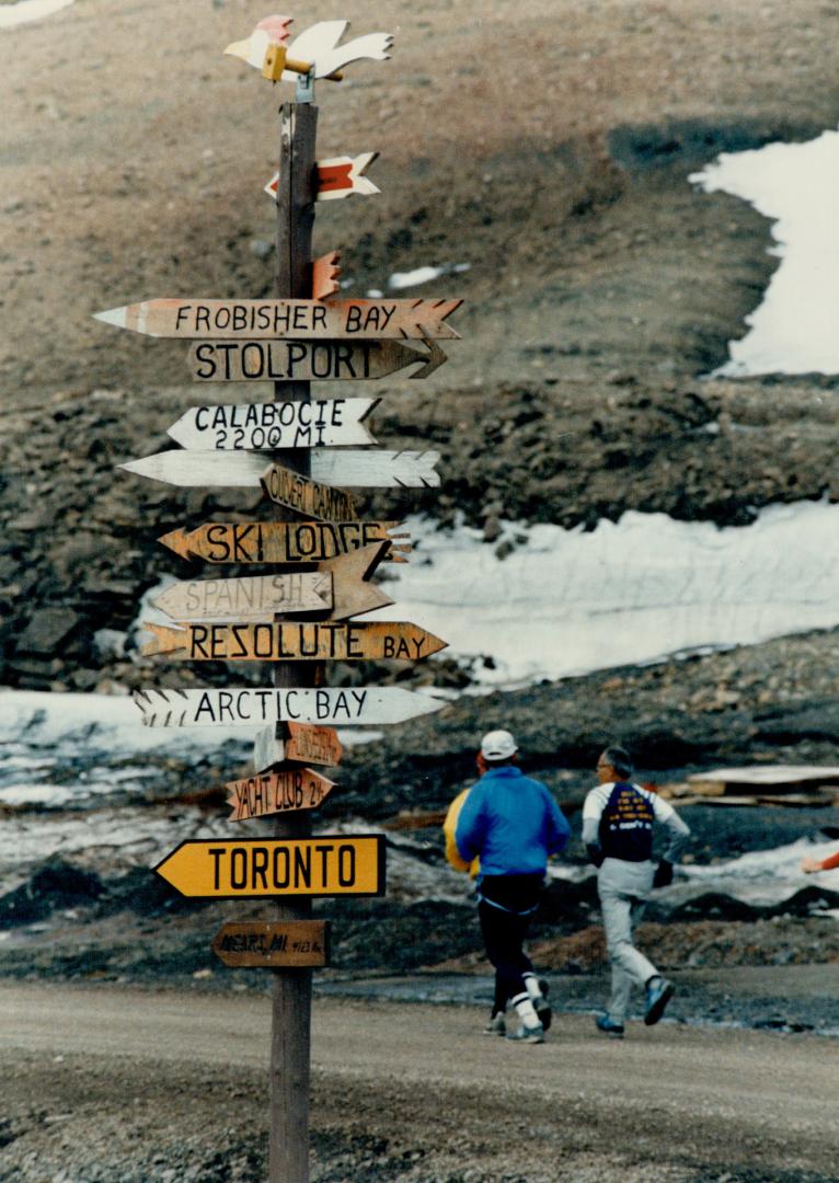 Runners pass signposts on the Midnight Sun Marathon Course