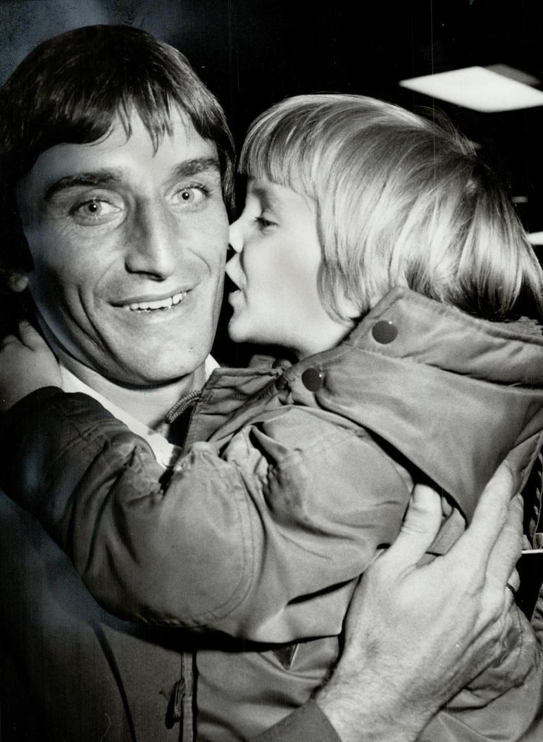 Best fan: Mike Stojanovic get a kiss from his best fan, 3-year-old son Doug, after soccer team arrived at Toronto International Airport to a quiet reception last night