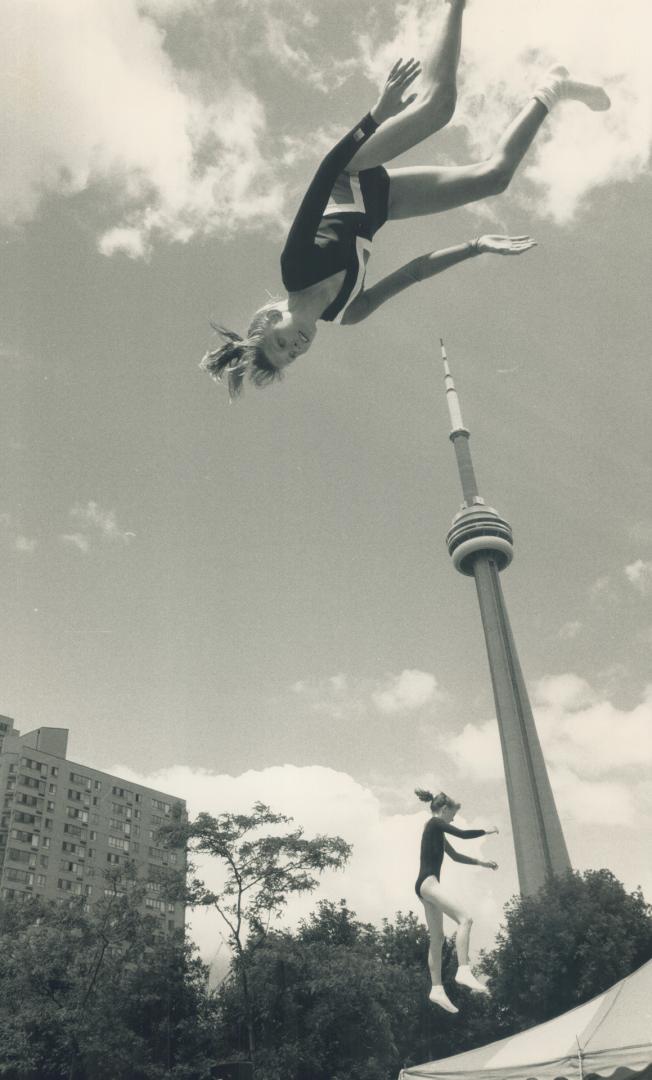 Head over heels. Trampoline gymnast Kystine McDonald of Great Britain, top, does a flip yesterday at Harbourfront, while a competitor works out nearby(...)