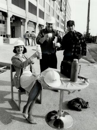 Future toast: Ann Tyndal, Harbourfront's director of programming, hoists container of coffee with workmen outside the soon-to-be completed Terminal Warehouse building