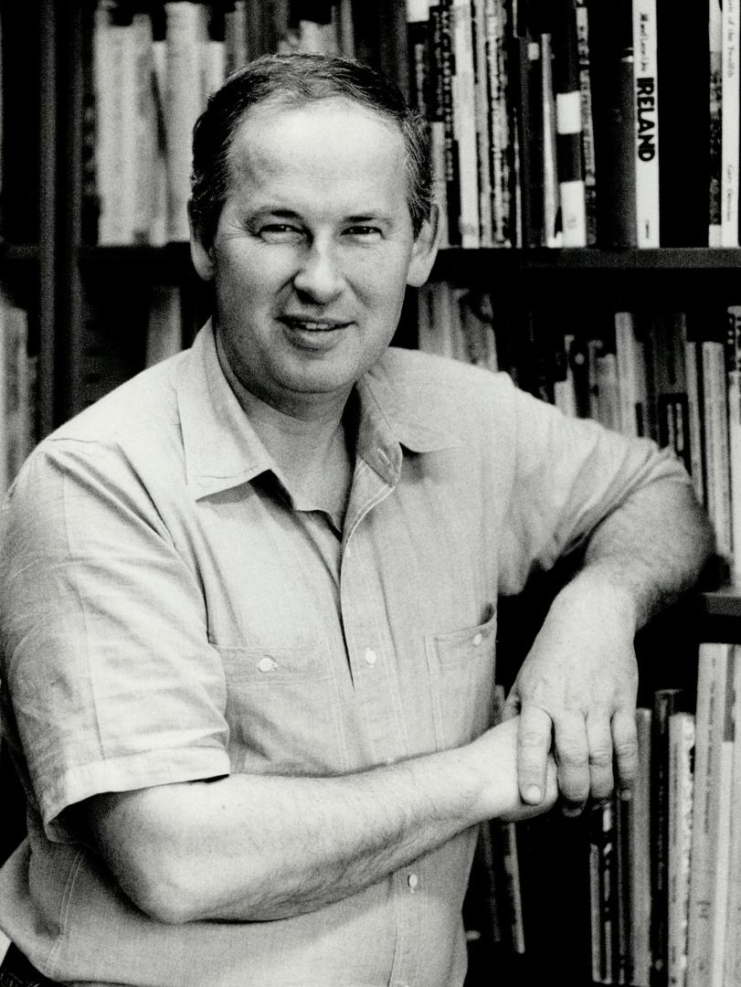 A Caucasian middle-aged man in a short-sleeved dress shirt poses, while leaning against a range…