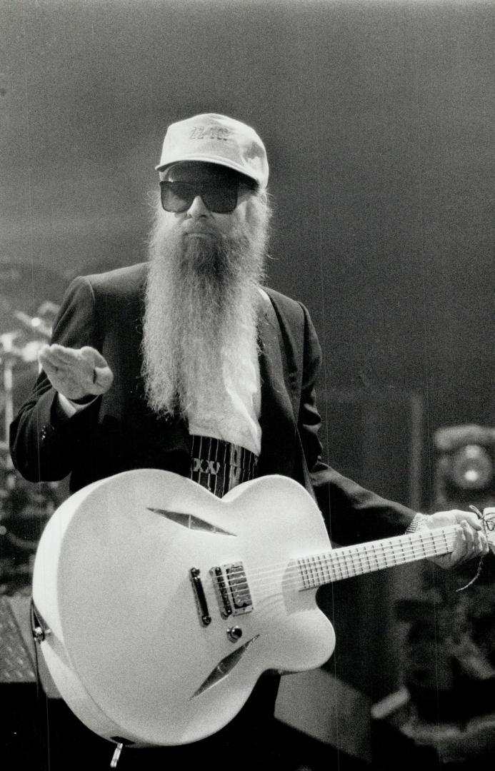 Hairy Godfather of Rock: Billy Gibbons looks sultably goofy in sunglasses, black suit, white guitar, pink baseball cap and two-foot-long beard, at Maple Leaf Gardens