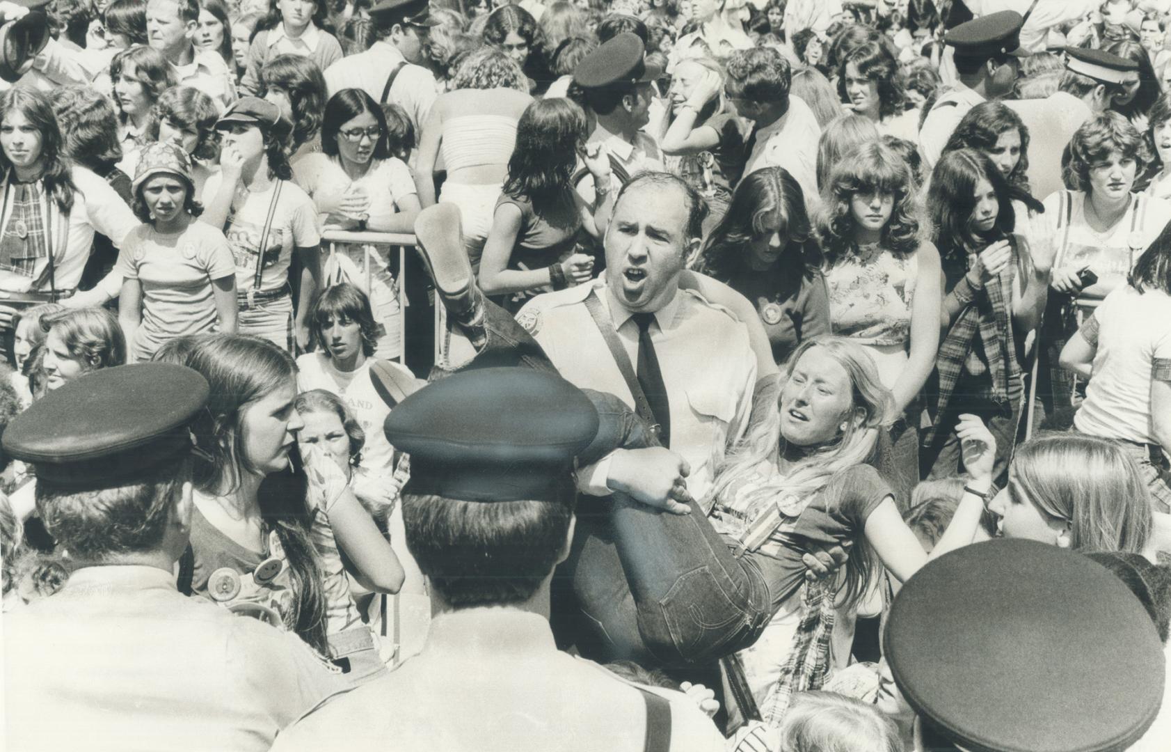 Overcome with the excitement of seeing the Bay City Rollers, a girl faints and is carried out of the crowd at Nathan Phillips Square yesterday. The Sc(...)