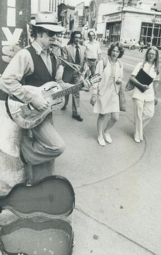 Street Musician Eric Stine strums his guitar and plays his harmonica on Yonge St