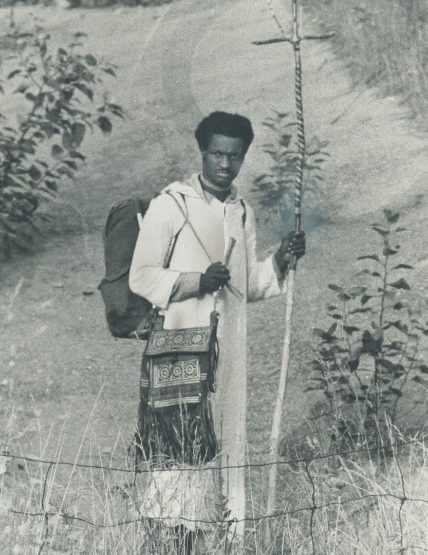 On his way from Mosport after doing his thing, whatever that may have been, a rock festival fan leaves grounds, carrying a cross, to hitchhike home