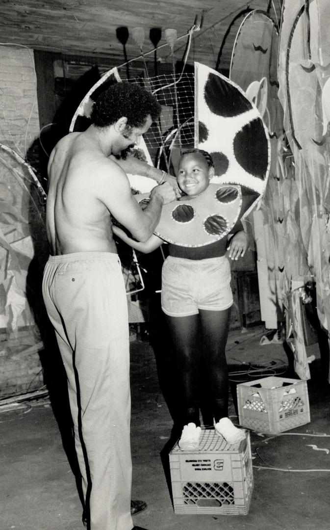 All set: Surrounded by other elaborate costumes for the Caribana parade, Whitfield Belasco adjusts Sasha Rodulfo's outfit, which is almost complete