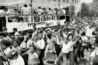 As musicians belt out a tune, a group of joyful youth whoop it up at the parade